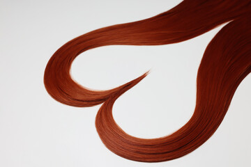 Poster - Red hair strands in shape of heart on white background, closeup