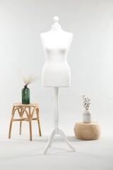 Sticker - One female mannequin on stand, stool, pouf and vases with plants against light background