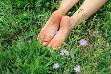 Canvas Print - Woman lying barefoot on green grass outdoors, closeup