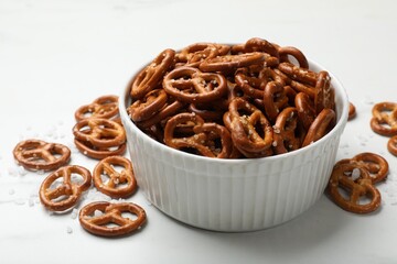 Poster - Tasty pretzel crackers with salt on white table, closeup