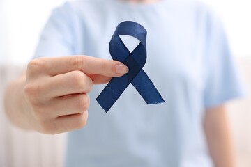 Wall Mural - Woman with dark blue ribbon on light background, closeup. Arthritis disease and colon cancer awareness