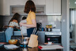 © qunica.com - A relaxed group of friends preparing a meal in a modern kitchen setting. The image captures a sense of teamwork and friendship during a casual cooking session.