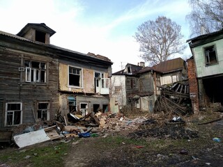 An abandoned, crumbling wooden house with shattered windows and piles of debris. The decaying structure is surrounded by rubble, creating a haunting and desolate urban decay scene.