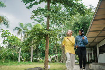 two young women in hijab exercising with headphones in the morning at the park