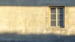 © Fomo Creative - A Single Window on a Yellow Stone Wall with Sunlight Casting Shadows