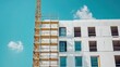 © Zidan - A white building under construction with scaffolding and a crane against a clear blue sky.