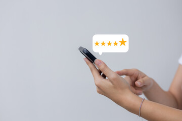 close up on customer woman hand pressing on smartphone screen with gold five star rating feedback icon and press level three rank (best) for give score point to review the service business concept	
