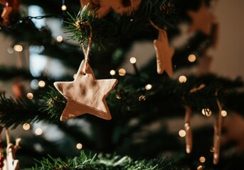 Wall Mural - Handmade clay star ornament is hanging on a christmas tree with lights