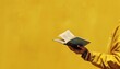 © Mahmud Creative - Female hands holding a book on a yellow background.