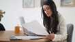 © luisrojasstock - Businesswoman working from home reviewing documents with a concerned expression