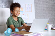 © wpadington - Happy smiling Afrcan American kid student working on his hometask using laptop computer. Distant education, remote studying concept