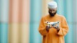 © JoxyAimages - A man wears orange attire, focused on controlling a hovering drone against a multicolored backdrop, symbolic of modernity, technology, and concentration.