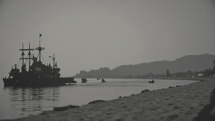 Vintage black-and-white photograph of a naval ship near a calm shoreline