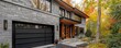 © Abdul - Panoramic image of a Montreal home with grey stone and wood accents, black garage, amid vibrant autumn hues