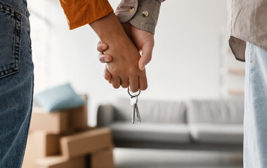 closeup of young couple holding hands and new house key, moving in together. unrecognizable boyfrien
