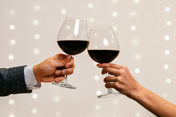 Toast for us. Romantic couple holding and clinking two glasses of red wine on date in restaurant, closeup, copy space