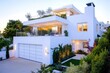 © Abdul - High-definition image of a modern house with white walls, a large garage, rooftop terrace, and a garden, under evening light