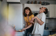 © qunica.com - Two young friends share a joyful moment as they laugh together in a modern kitchen setting, highlighting friendship and happiness in daily life.