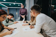 © qunica.com - A group of students focused on a drawing activity in a classroom setting, guided by a teacher. The scene depicts learning, creativity, and collaboration.