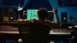© DC Studio - Cheerful energic audio engineer dancing on his own music creation in professional studio, editing a recording on mixing console and daw software. Sound designer processing tracks. Camera B.