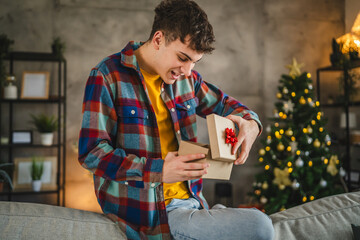 Surprised young adult man open christmas gift at home