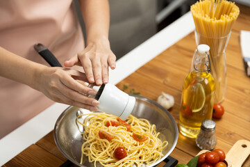 Close up of hand chef influencer cooking spaghetti mix ingredient taking to frying pan, putting seasoning and tasty sauce to make good flavor, Concept of presenting homemade food at studio. Postulate.