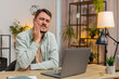 © Andrii Iemelianenko - Caucasian young man freelancer sitting at home office table feeling toothache touching mouth with hand, painful expression because of dental illness. gum disease, dental disease concepts. Lifestyle.