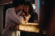 © qunica.com - Two people sharing a fun and engaging conversation over drinks at a lively bar. Ideal setting for a night out with friends.