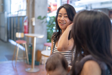 Two Taiwanese women in their 30s wearing casual outfits hold a 6-month-old baby and chat together on Dihua Street in Taipei City, Taiwan, in September.