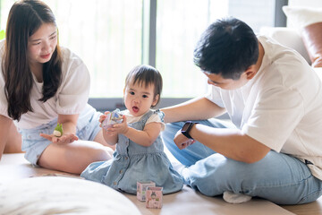 A 1 year old Taiwanese girl spending time playing happily with her parents, a man and woman in their 20s, in a room of a high rise apartment in Taichung City, Taiwan.