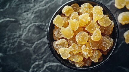 Poster - Candied ginger in black bowl on dark stone background Top view Copy space : Generative AI