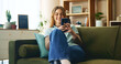 © AzeemudDeen/peopleimages.com - Happy, woman and relax with phone on couch for communication, social media and notification update. Smile, girl and mobile for reading message, online chat and texting of entertainment game at house