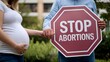 © Юлия Жигирь - A pregnant woman and a man holding a placard with the words 'Stop abortion!'.