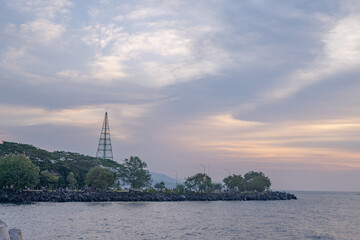 Sunset over the Ocean with a Tower.  A beautiful sunset over a calm ocean with a tall tower standing on the shore.