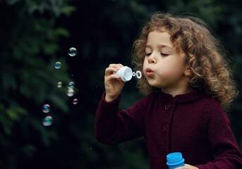 little girl blowing bubbles in a park: joyful playtime and childhood fun outdoors