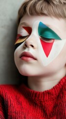 Child with colorful geometric face paint rests peacefully in a red sweater, AI