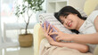 © Prathankarnpap - Cheerful young Asian woman lying on sofa and using mobile phone.
