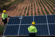 © VIEWFOTO STUDIO - Service worker in PPE. cleaning  with solar panel with wind turbine on background.