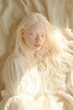 © Iryna - A woman with blonde hair and white makeup is lying on a bed. The image has a dreamy, ethereal quality to it, with the woman's hair flowing and her eyes closed. Scene is one of relaxation