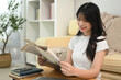 © Prathankarnpap - Smiling young asian woman reading newspaper in the morning at home