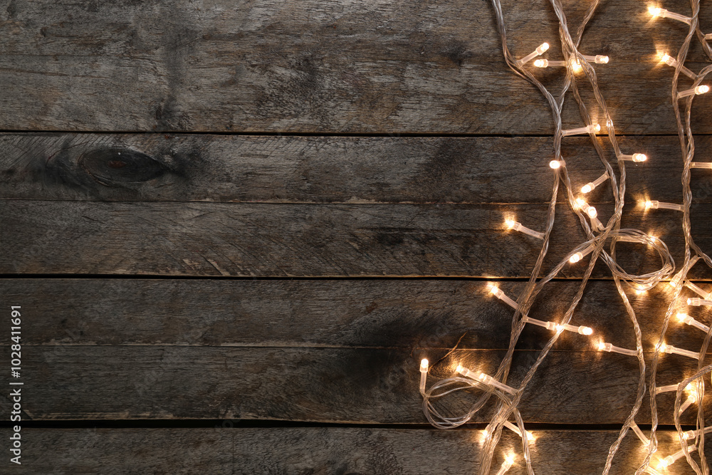 Glowing Christmas lights on dark wooden background