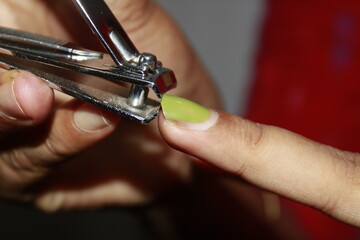 A close-up of woman's hand holding a nail clipper is cutting her nails to keep hygienic. Concept of personal hygiene care to reduce the chance of illness.