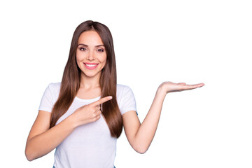 Wall Mural - Portrait of lovely millennial holding hand pointing to ads with her index finger isolated over blue background