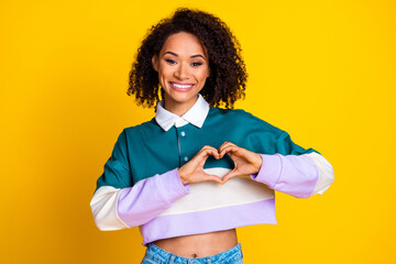 Poster - Portrait of good mood appreciative girl with wavy hairdo wear striped shirt show heart symbol on chest isolated on yellow color background