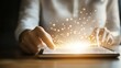 © Aris Suwanmalee - A close-up of a person's hand interacting with a tablet, creating a magical digital glow of light and energy effects.