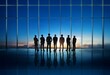 © YiuCheung - Silhouettes of six businesspeople stand looking out a large window at a cloudy sunset.