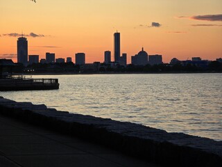 Poster - Boston skyline at sunset with silhouetted buildings and calm waterfront.