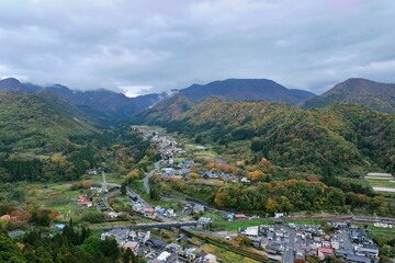 Aerial view of a village in a mountainous landscape with autumn foliage.