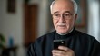 © Lion - Senior priest using a smartphone and talking on a video chat, minimal background focusing on his conversation.
