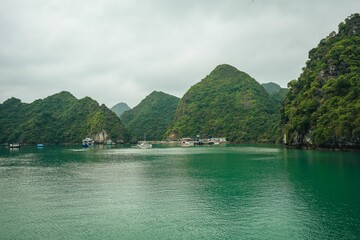 Scenic view of limestone karsts and emerald waters in Halong Bay under a cloudy sky